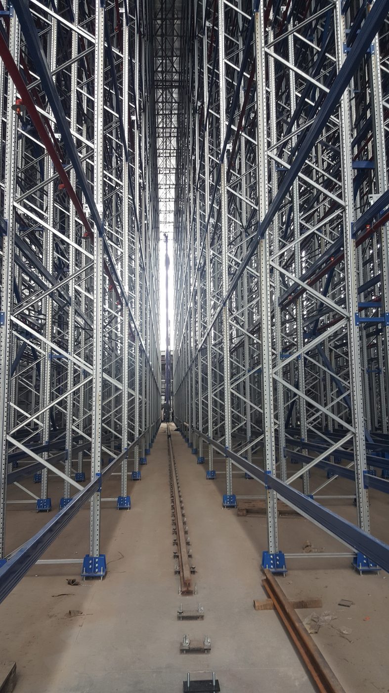 Pasillo interior de un almacén autoportante de gran altura con rieles de transelevador